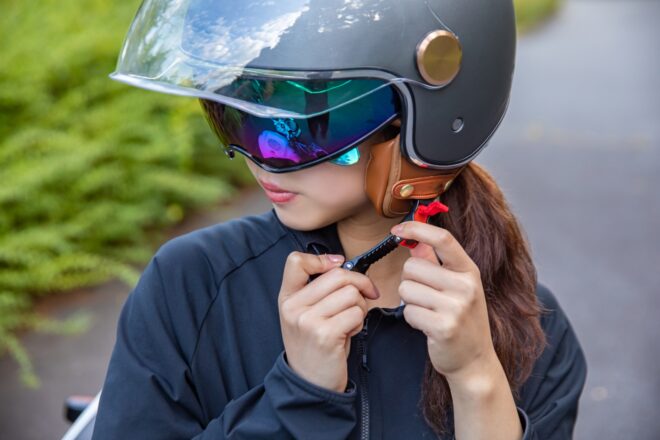 ツーリングで危険を回避するためにヘルメットを着ける女性のイメージ